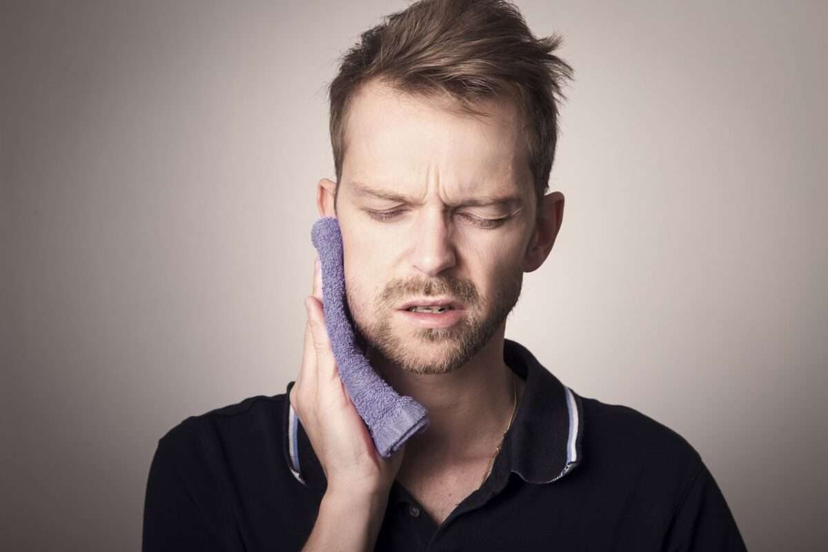 man holding hot compress to jaw
