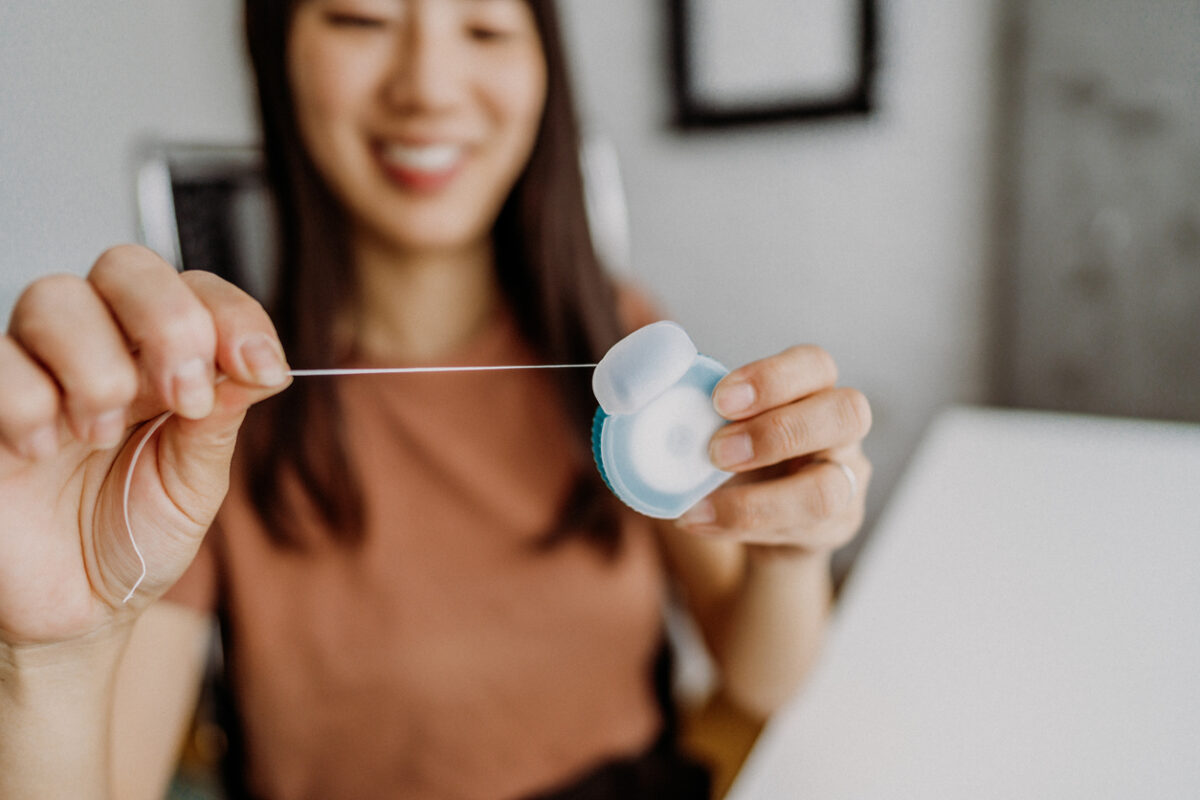 Woman at a desk holding a contact lens case with a lens, preparing to insert contact lenses into her eye (close-up).